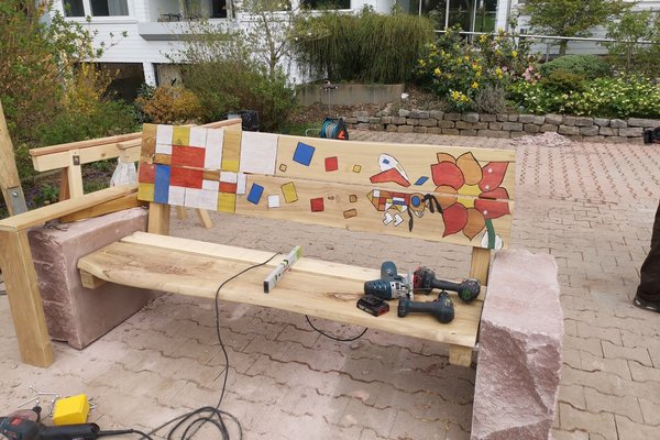 Augustinum Heidelberg Gartengestaltung Eine angemalte Holzbank, auf der Werkzeuge liegen