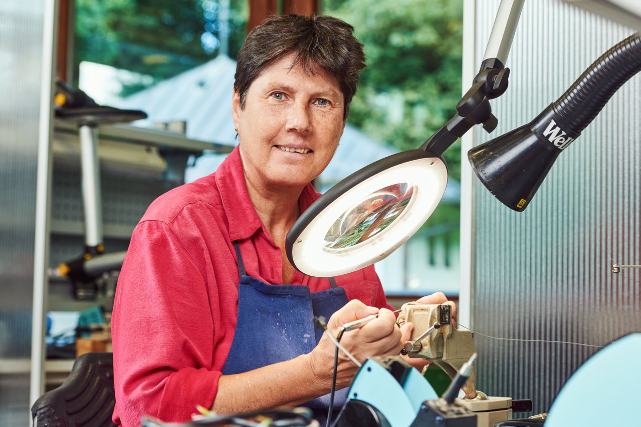 Elektronikabteilung Eine Klientin arbeitet mit einem Vergrößerungsglas in der Elektronikabteilung