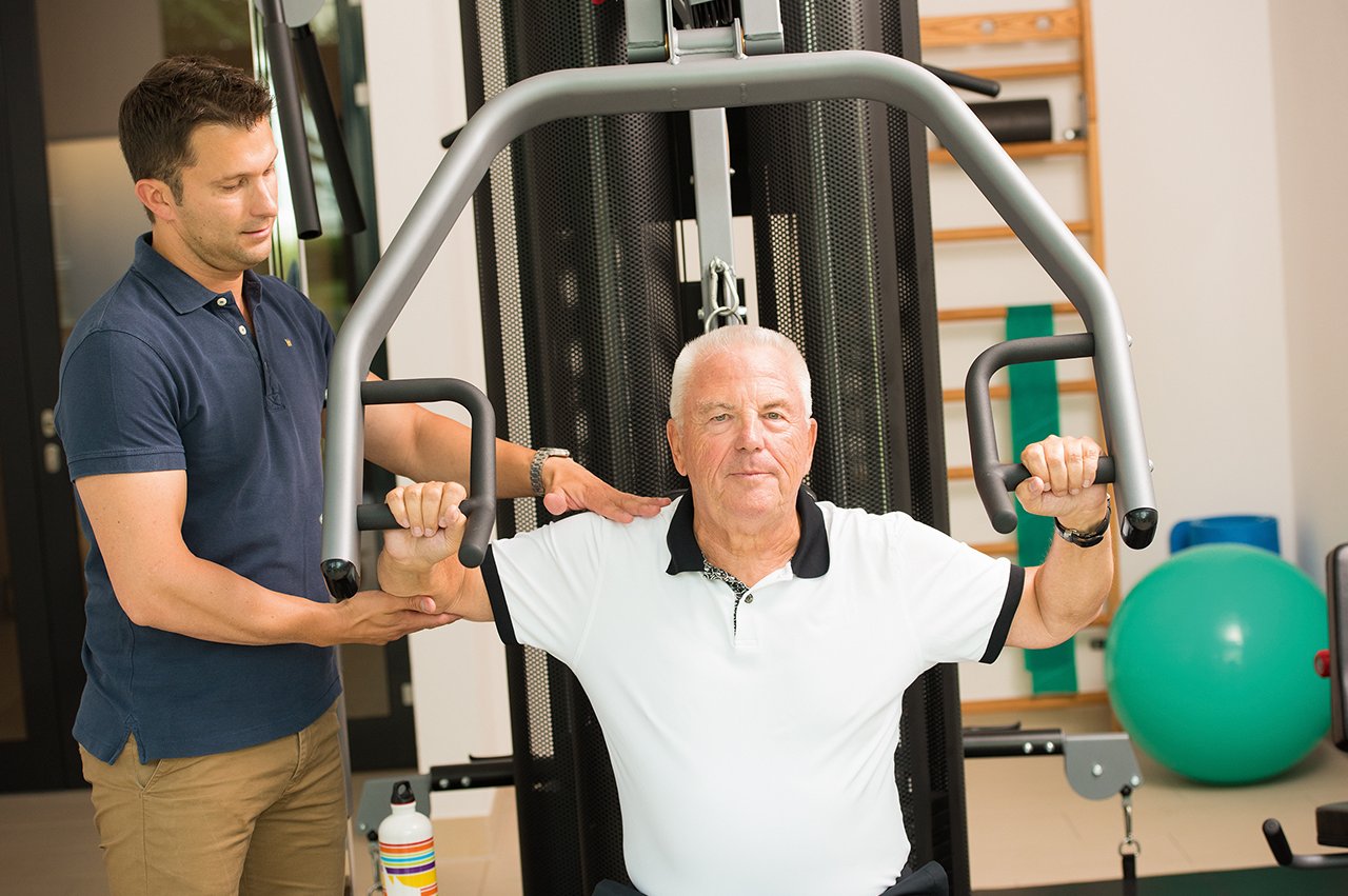 Gerätetraining Fitnesstrainer und Bewohner des Augustinum beim Gerätetraining