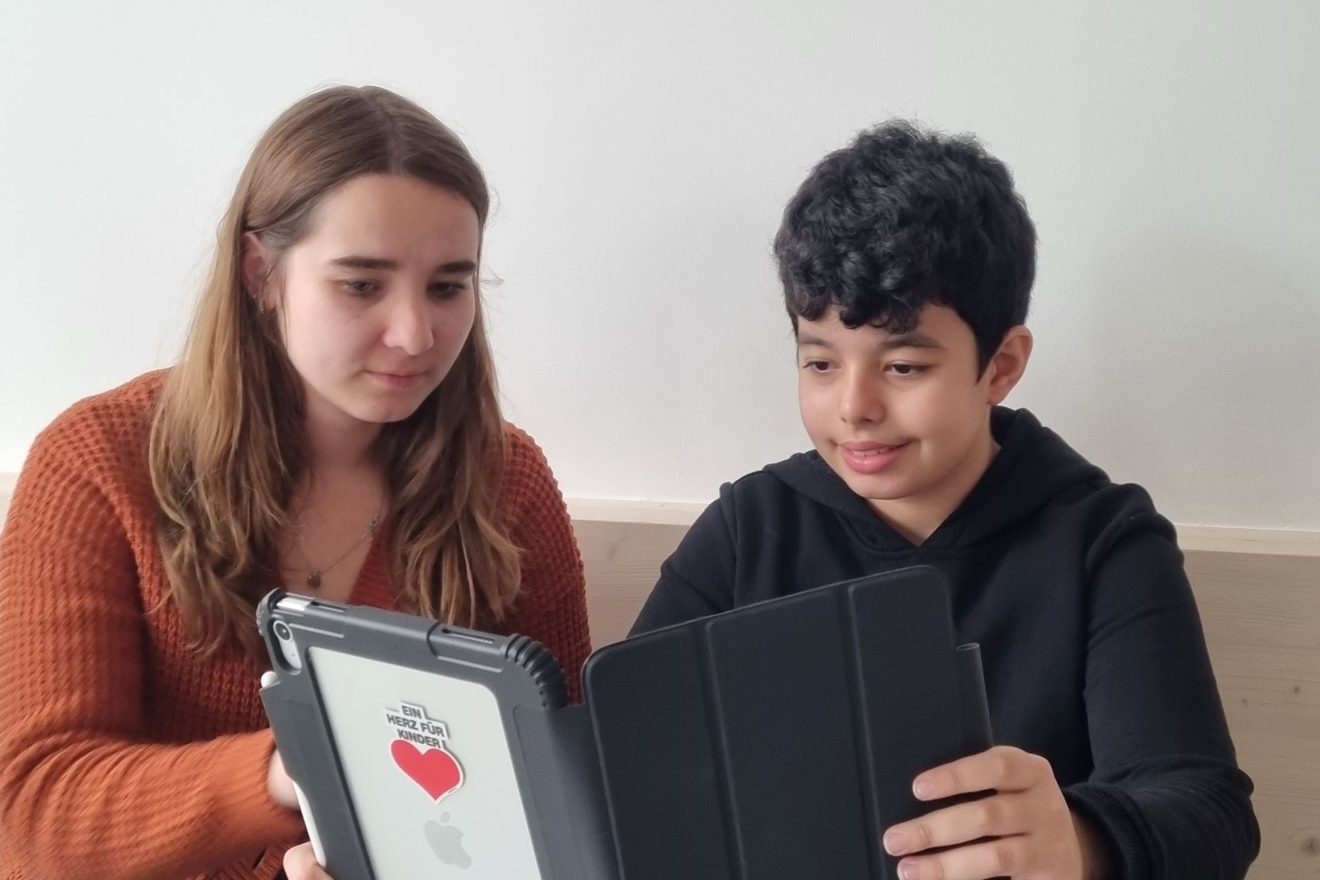 Augustinum Tagesstätte iPads Eine Junge und eine Mitarbeiterin der Augustinum Tagesstätte schauen gemeinsam in ein iPad