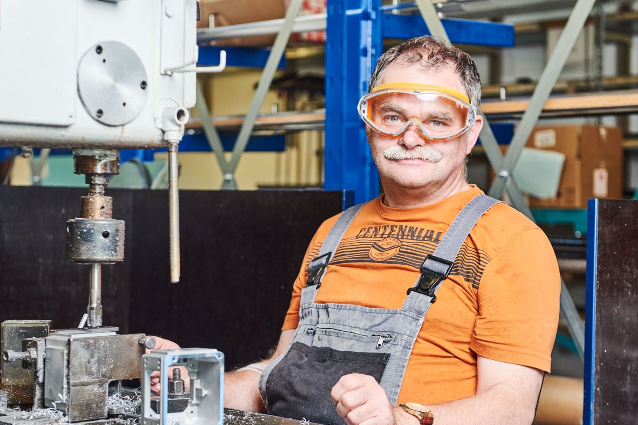 Mann mit Schutzbrille Ein Klient sitzt an einer Maschine der Metallverarbeitung und trägt eine Schutzbrille