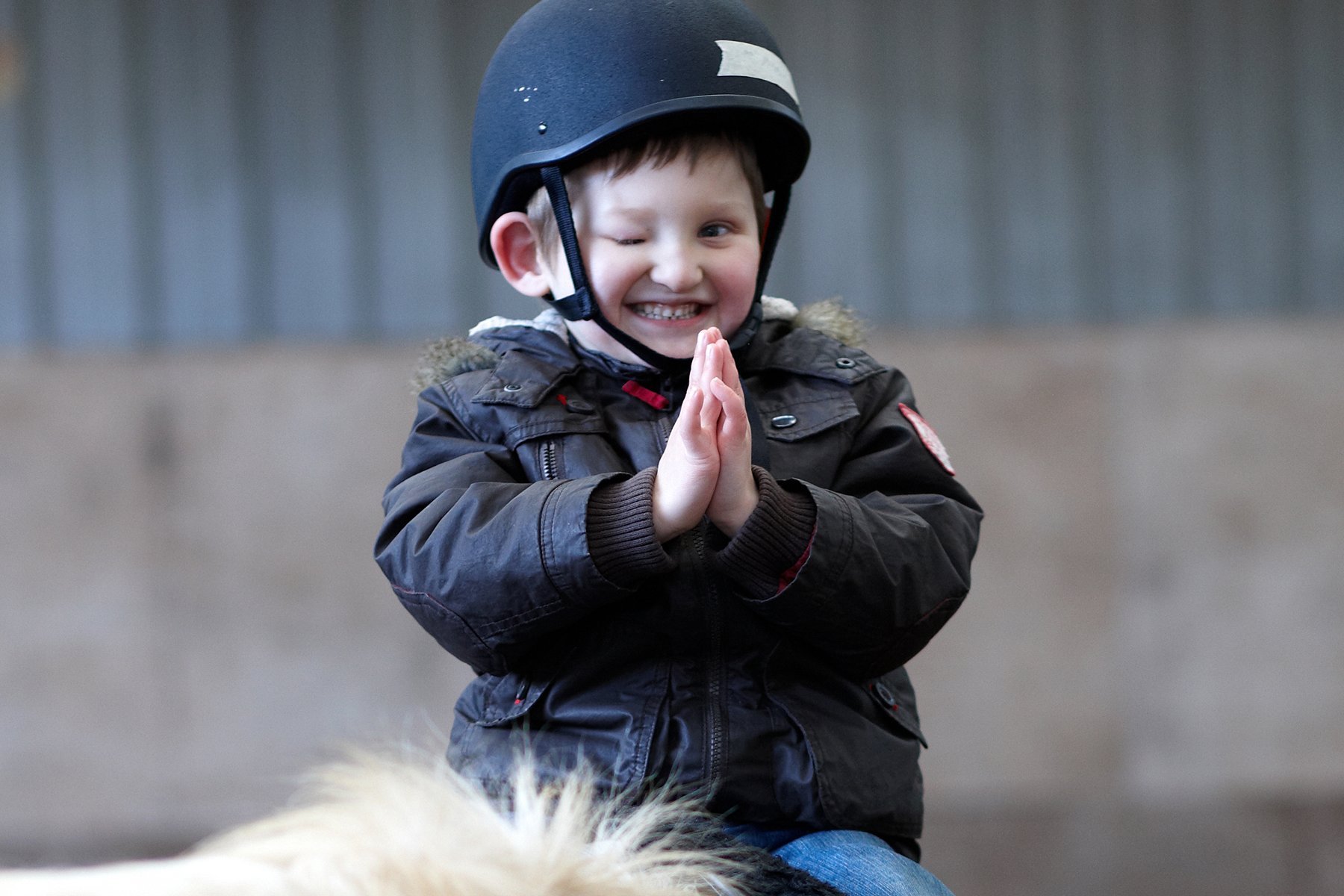 Therapeutisches Reiten in den Augustinum Frühförderstellen Behinderter Junge mit Reithelm auf einem Pferd