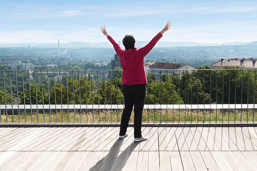 Qi Gong Frau mit ausgebreiteten Armen auf einer Dachterrase