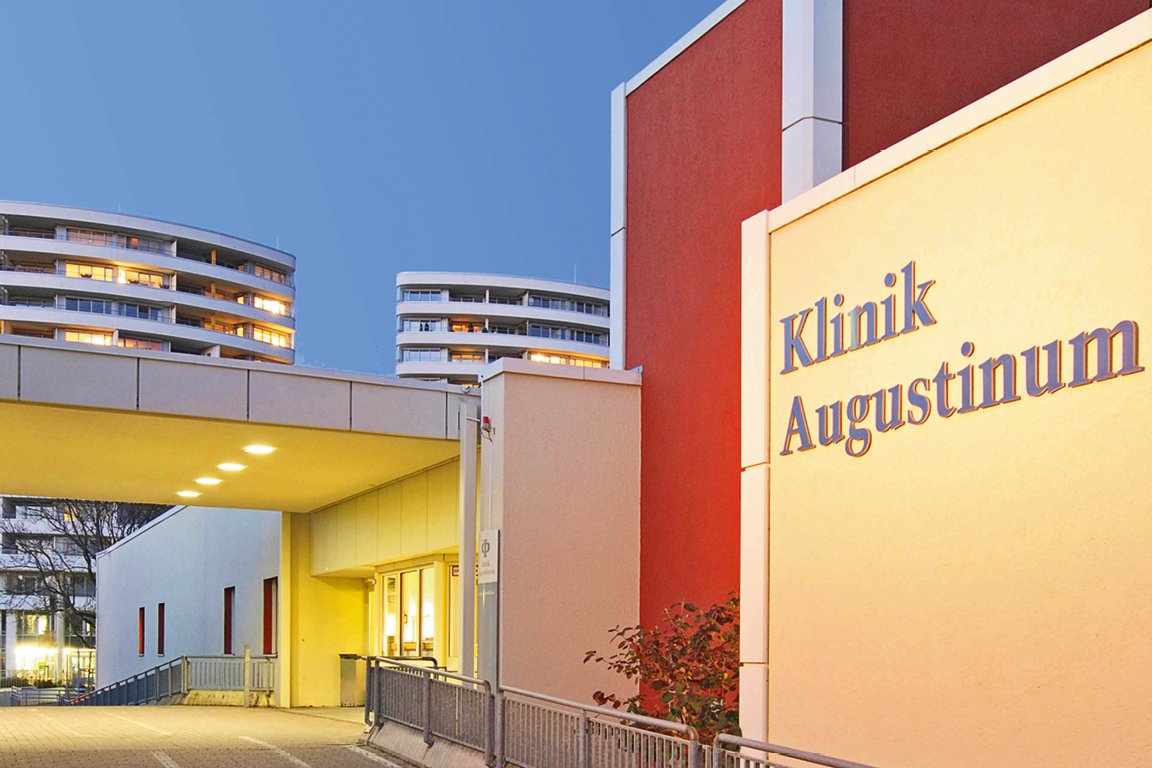 Außenaufnahme Augustinum Klinik Bild der Auffahrt und des Eingangsbereichs der Augustinum Klinik in der Dämmerung