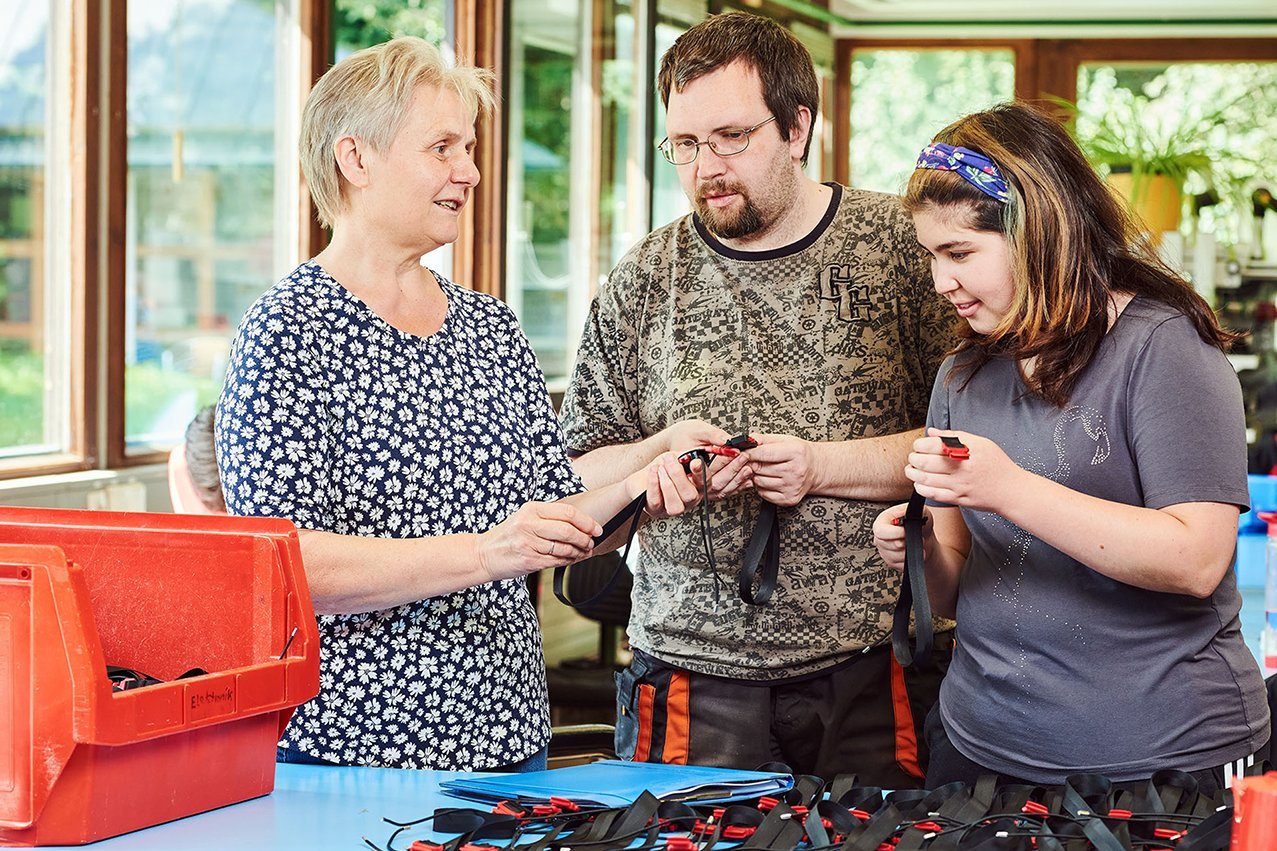 Konfektionieren Drei Klient*innen der Augustinum Werkstätten beim Konfektionieren und Verpacken