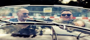 Hauptpersonen sitzen lachend im Auto Hauptpersonen sitzen lachend im Auto