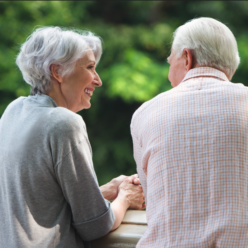 Augustinum Seelsorge Ein Seniorenpaar steht auf einem Balkon und lächelt sich an