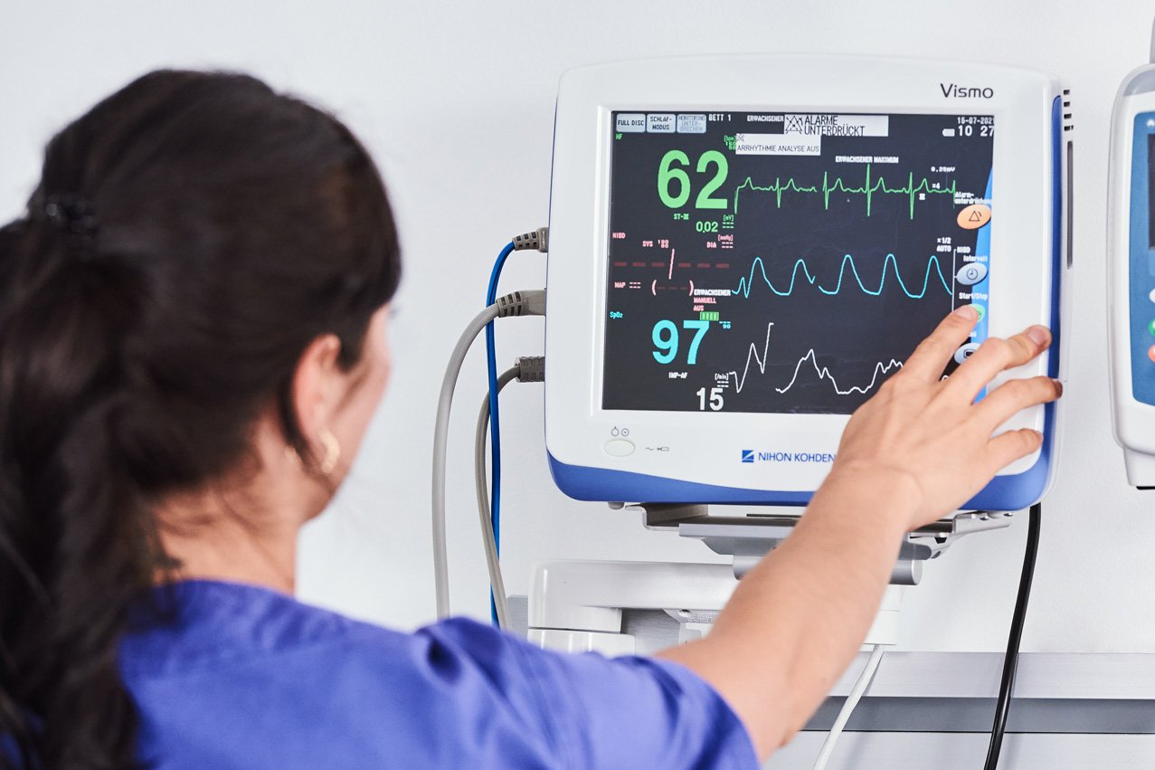 Überwachung von Vitalfunktionen am Monitor Eine Pflegerin kontrolliert blickt auf einen Bildschirm mit medizinischen Daten.