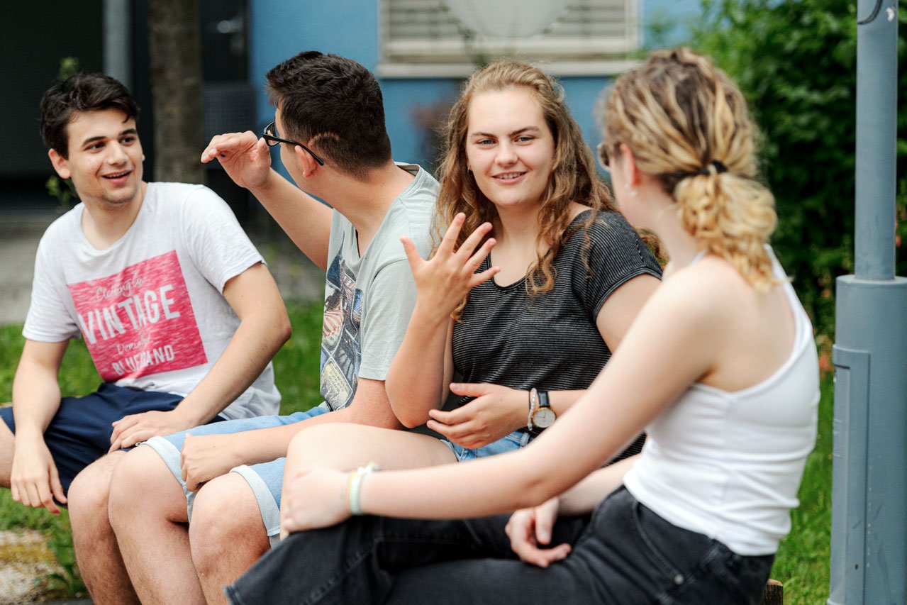 Jugendliche unterhalten sich in Gebärdensprache im Garten