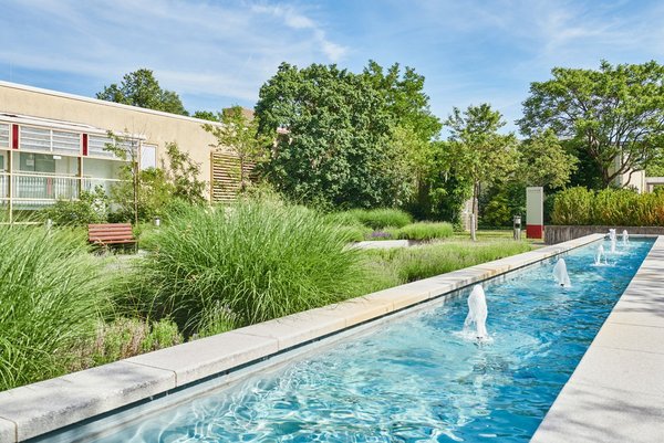 Aufenthalt außerhalb der Patientenzimmer Blick in den Garten vor der Augustinum Klinik mit Springbrunnen und Bäumen