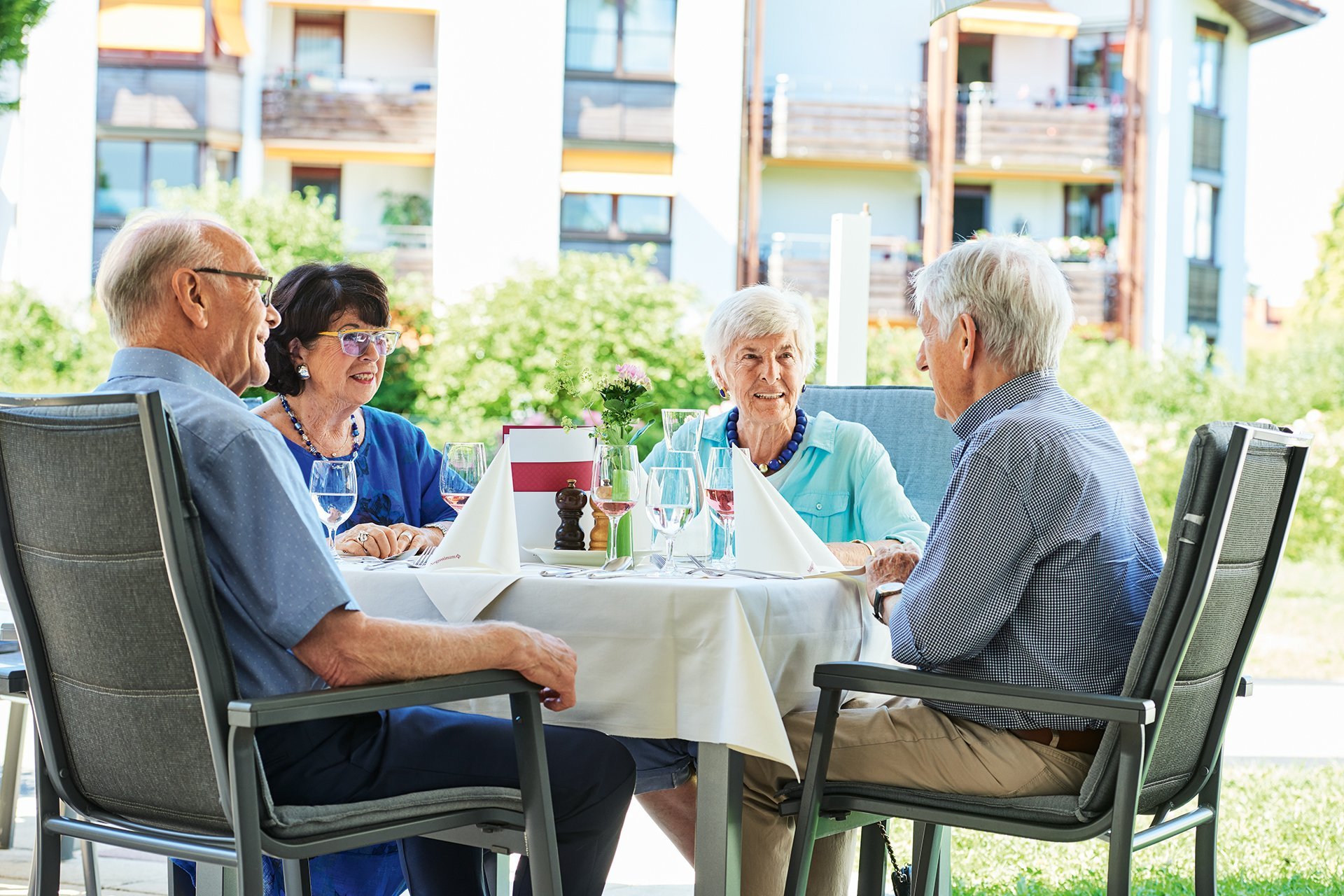 Augustinum Seniorenresidenz Dießen Restaurant Terrasse Vier Senior*innen sitzen an einem Tisch des Restaurants auf der Terrasse