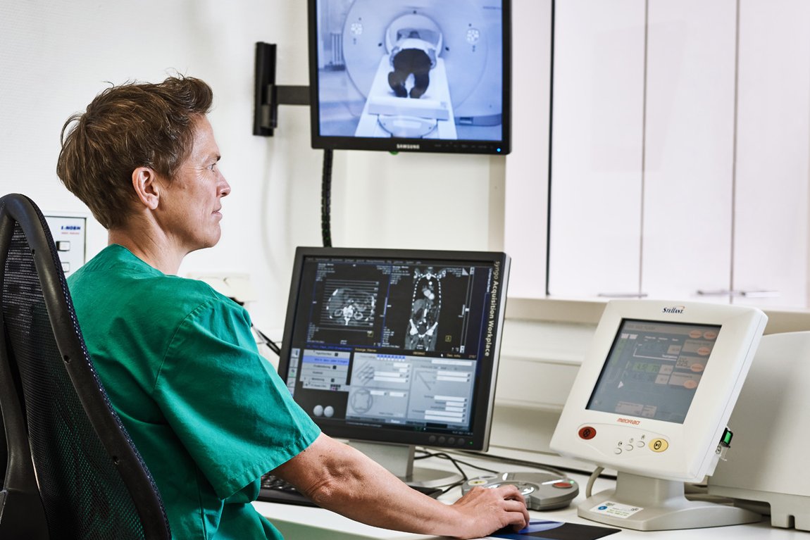 Computertomographie Eine Mitarbeiterin der Augustinum Klinik kontrolliert vor mehreren Bildschirmen sitzend eine Computertomographie