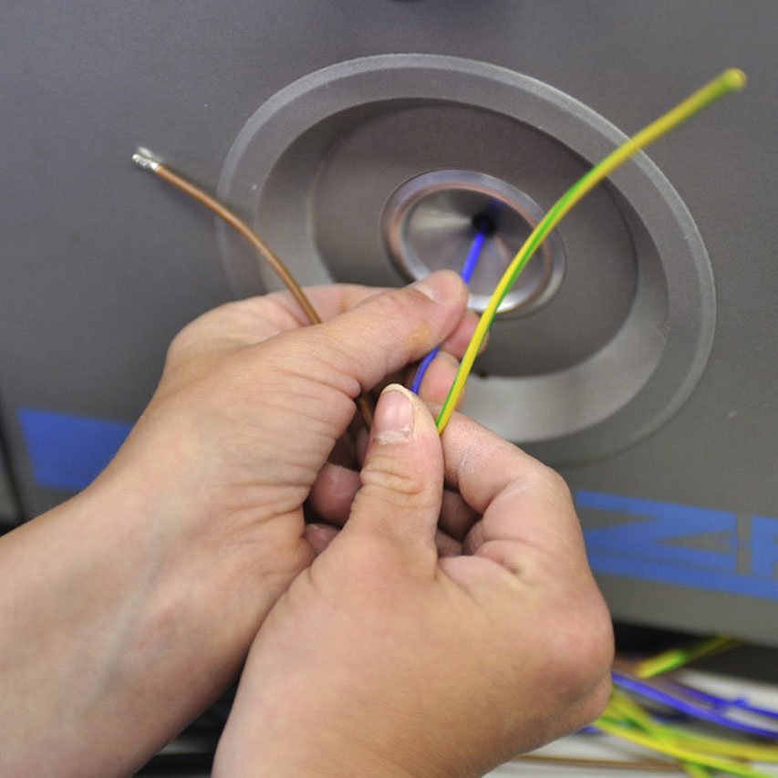 Kabelkonfektionierung Zwei Hände bei der Kabelkonfektionierung