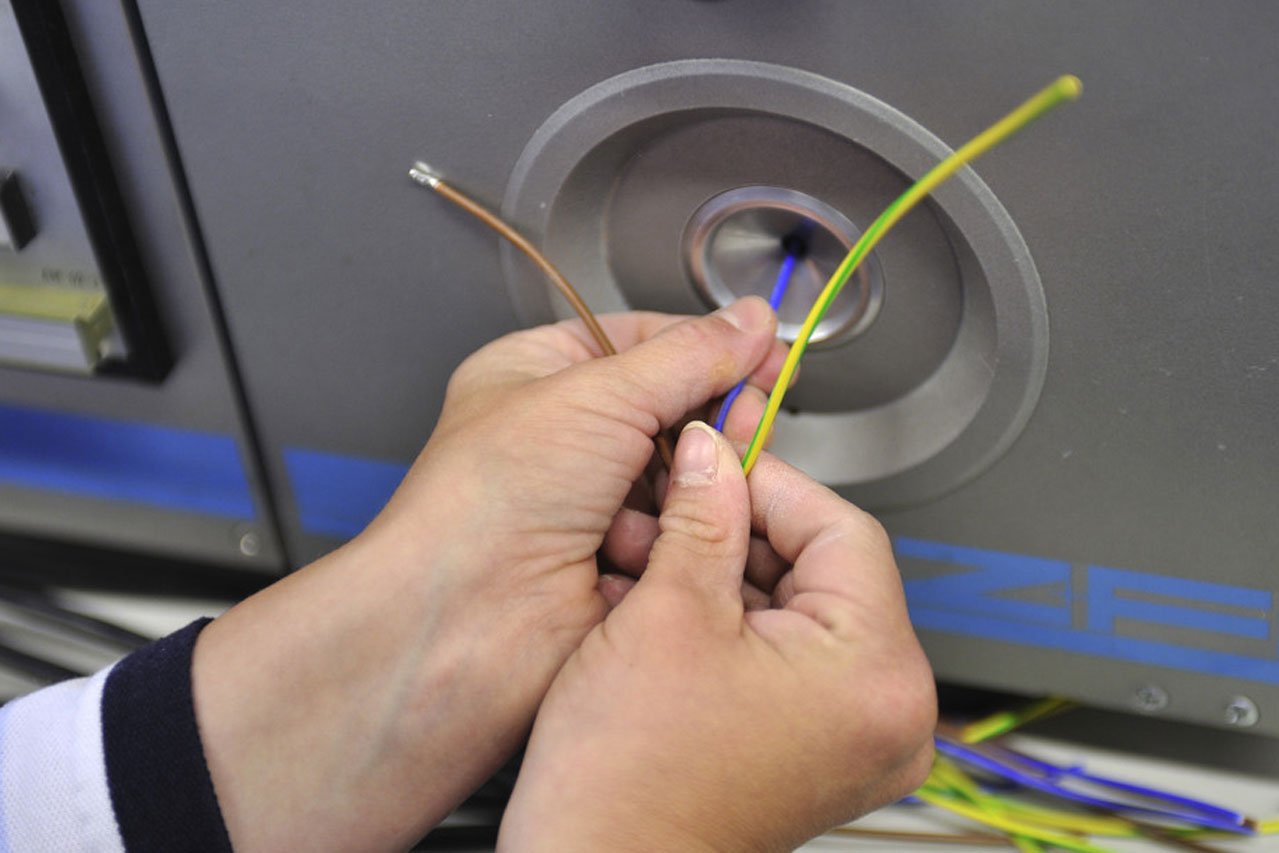 Kabelkonfektionierung Zwei Hände bei der Kabelkonfektionierung