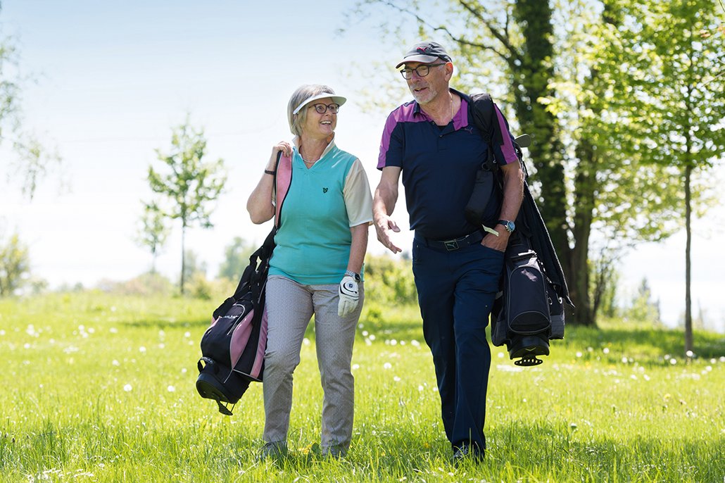 Augustinum Golf Cup Mann und Frau mit geschulterten Golfbags