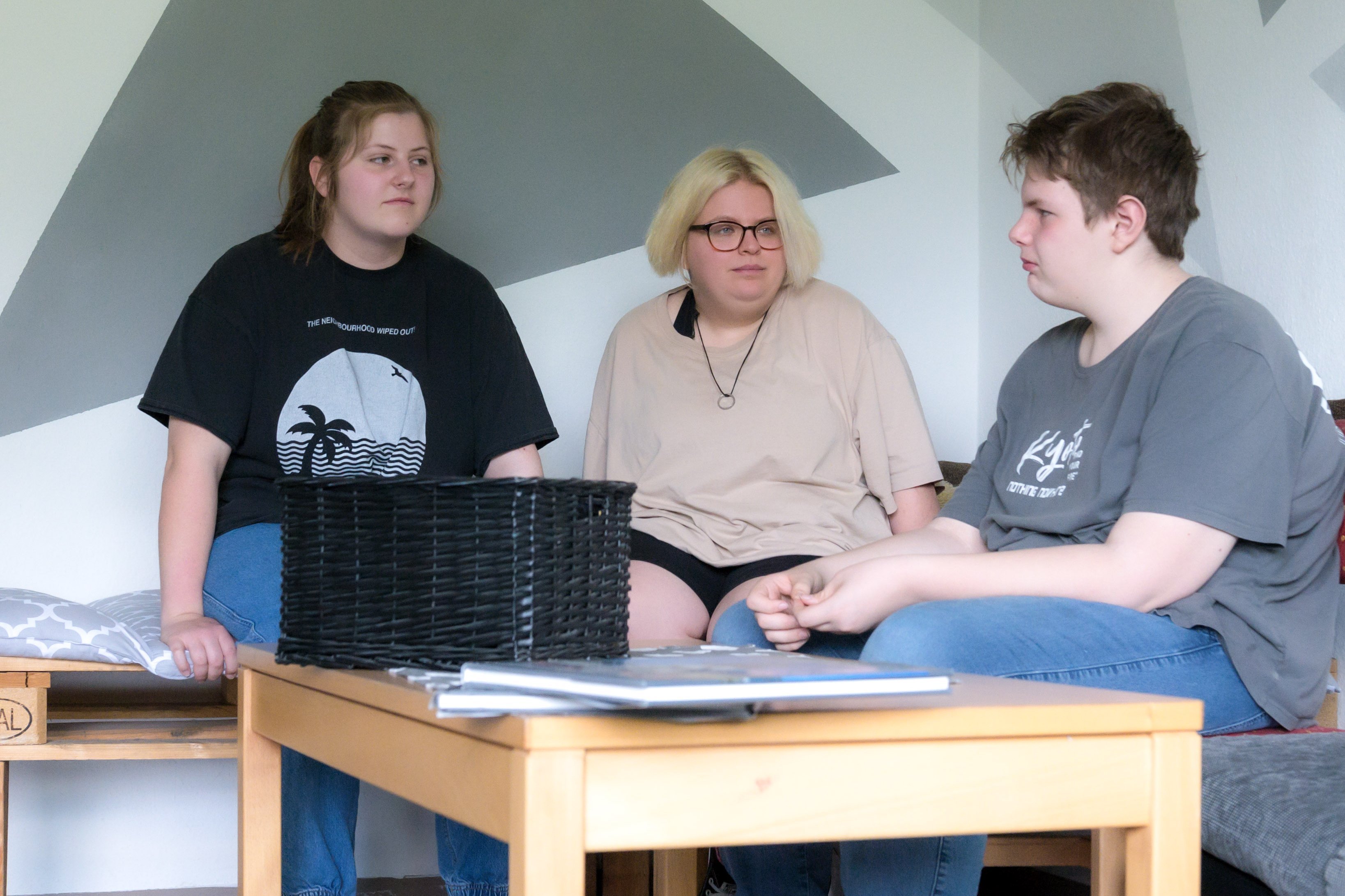 Drei Jugendliche sitzen auf einem Sofa und sprechen miteinander
