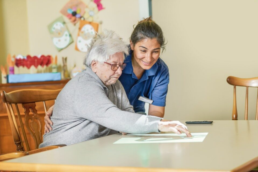 Augustinum Berchtesgadener Land Tagespflege Tovertafel Eine Mitarbeiterin und eine Bewohnerin der Tagespflege spielen ein Spiel, welches auf den Tisch projiziert wird