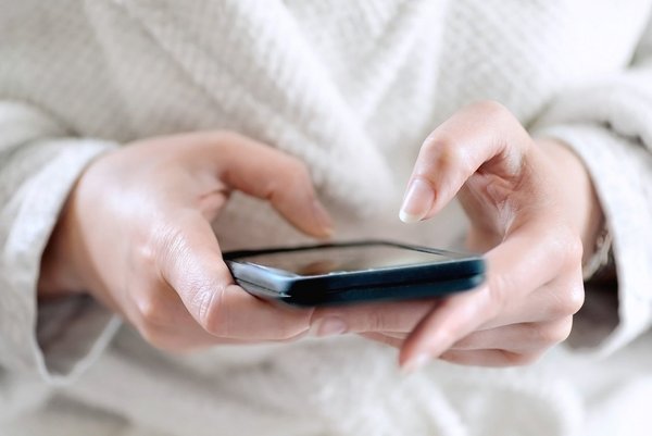 Telefon, WLAN und Fernseher Zwei Frauenhände tippen auf einem Smartphone