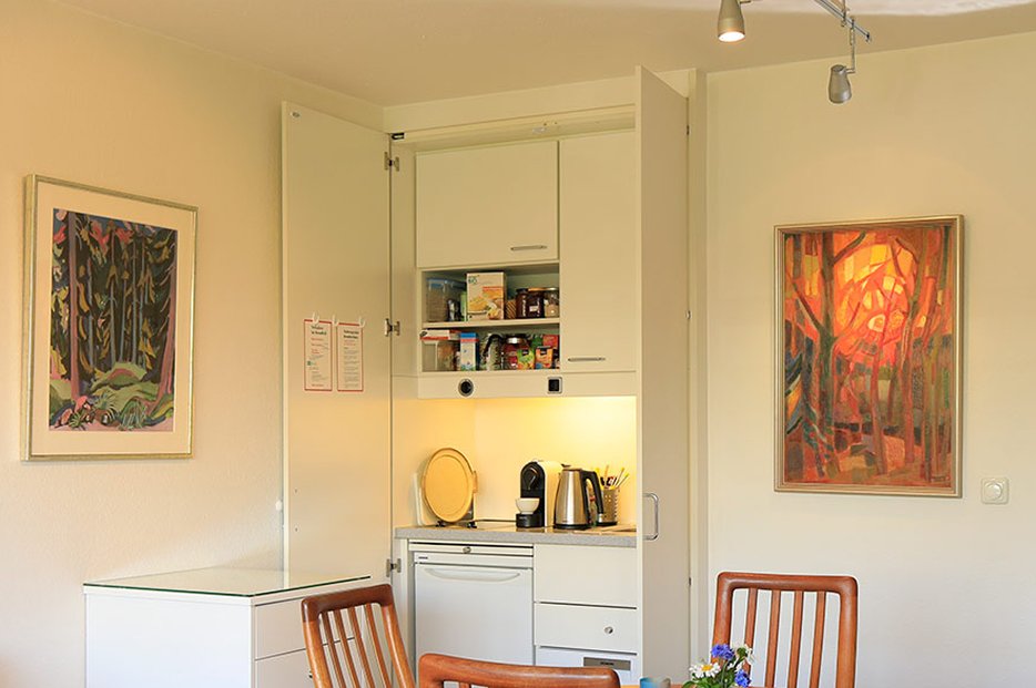 Zu jeder Wohnung gehört auch eine kleine Einbauküche, was auch Selbstversorgung möglich macht. Esstisch mit Stühlen vor Küchenelement