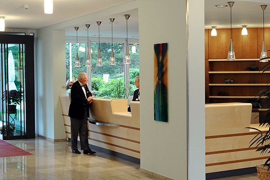 Rund um die Uhr stehen am Empfang freundliche Mitarbeiter*innen mit Rat und Hilfe bereit. Empfang mit Bewohner und Mitarbeiterin des Bewohnerservices