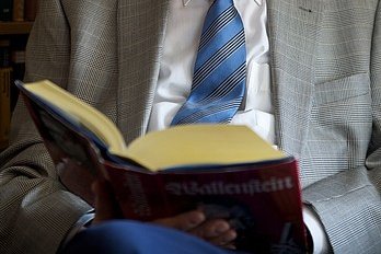 Augustinum Seniorenresidenzen Lesekreis Ein älterer Mann hält ein aufgeschlagenes Buch in den Händen