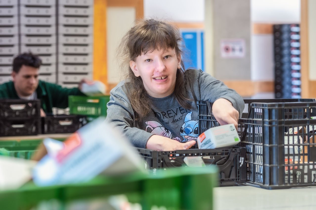 Kunststoffkisten einsortieren Eine Klientin der Augustinum Gärtnerei Holler sortiert Kresseschalen in Kunststoffkisten