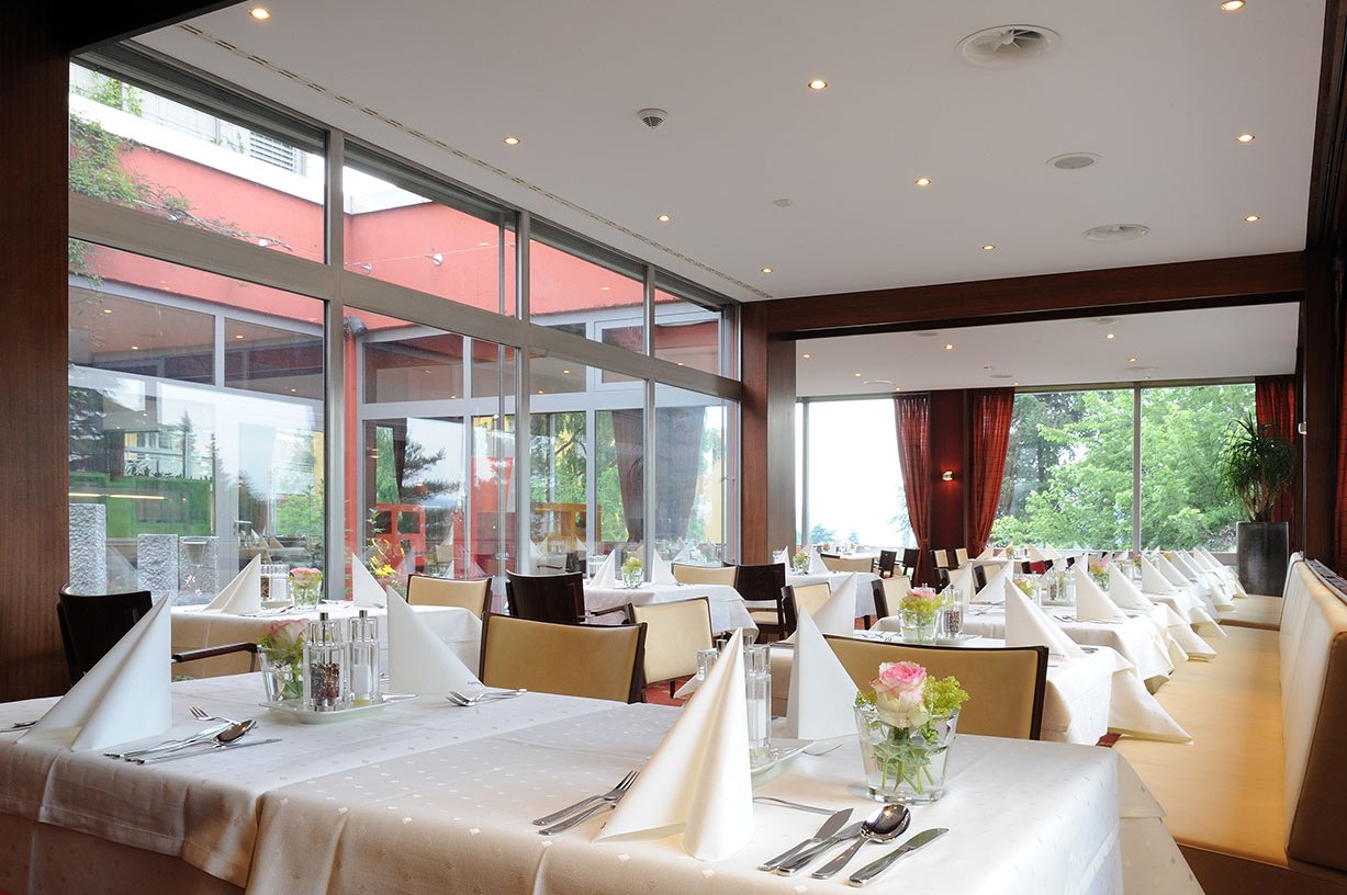 An festlich gedeckten Tischen treffen sich die Bewohner*innen im Restaurant zum Essen und zum Austausch von Neuigkeiten. An festlich gedeckten Tischen treffen sich die Bewohner*innen im Restaurant zum Essen und zum Austausch von Neuigkeiten.