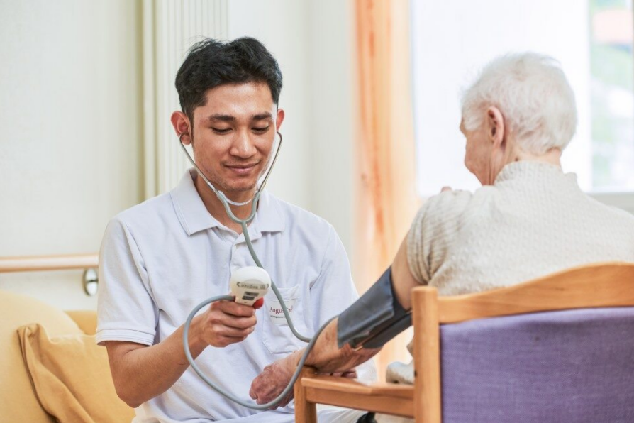 Augustinum Berchtesgadener Land Stationaere Pflege Blutdruck Ein Pfleger misst den Blutdruck einer Seniorin