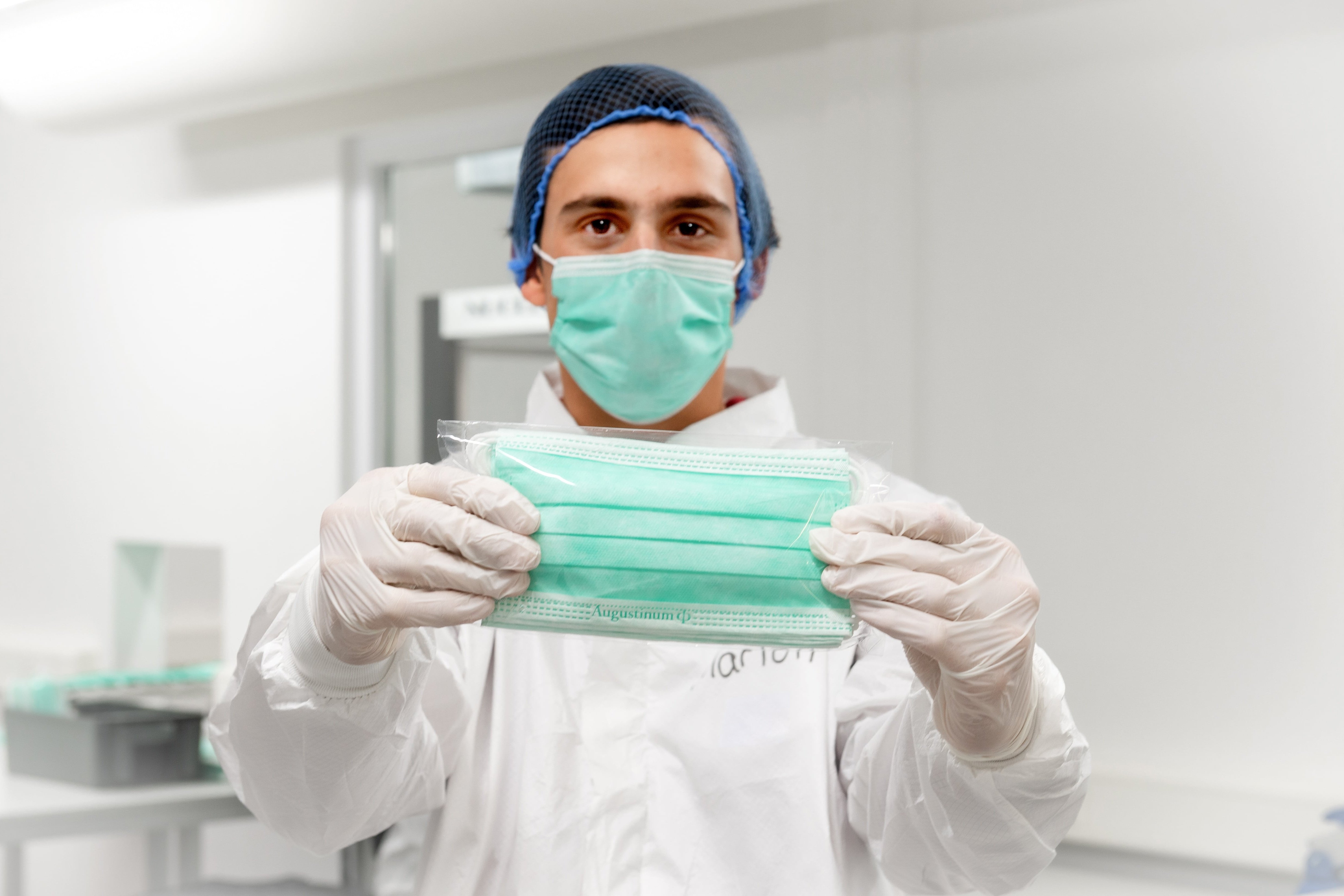 Maskenproduktion Ein Klient hält eine in den Augustinum Werkstätten produzierte medizinische Maske hoch