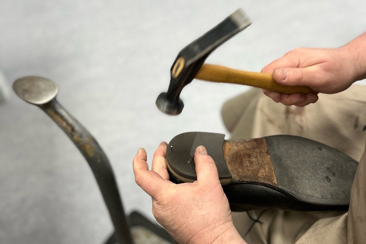 Augustinum Schusterei Schuhreparaturen Ein erneuerter Absatz wird an dem Schuh fixiert