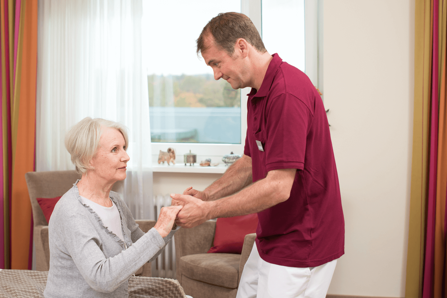 Tagesbetreuung für Menschen mit Demenz Pfleger hilft älterer Dame beim Aufstehen