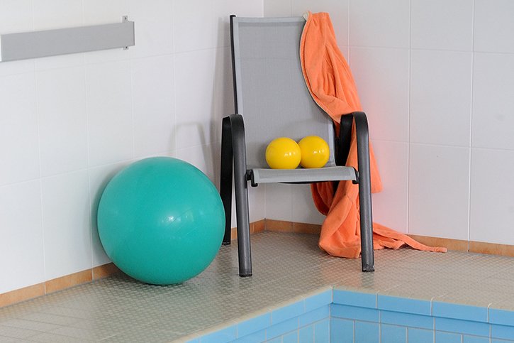 Wassergymnastik Gymnastikbälle und Stuhl am Rand eines Schwimmbeckens