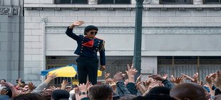 Michael Michael Jackson steht erhöht inmitten einer Menschenmenge mit ihm zuwinkenden Händen.