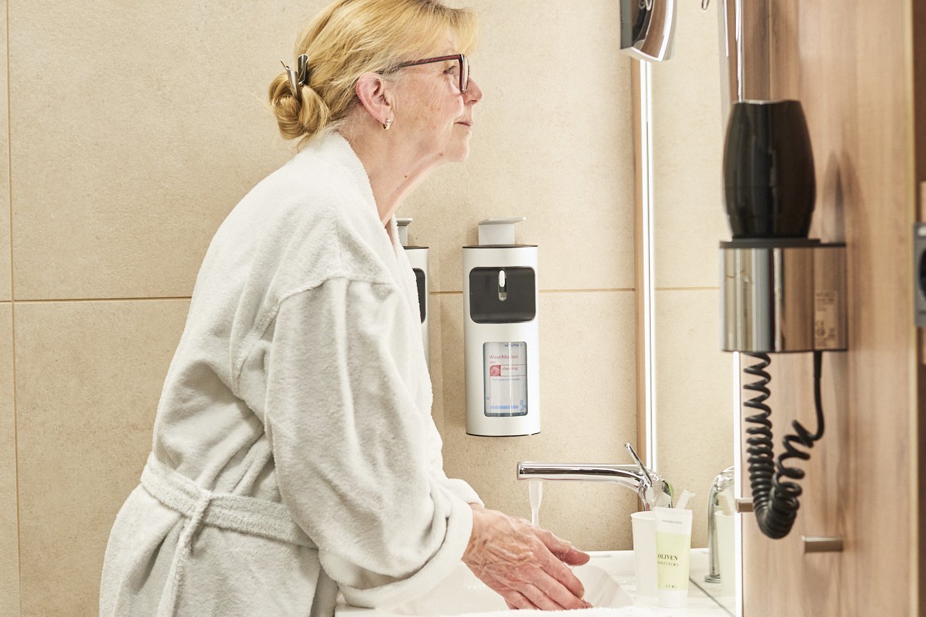 Augustinum Klinik Wahlleistungsstation Badezimmer Eine Patientin auf der Wahlleistungsstation wäscht sich im Badezimmer vor einem Spiegel die Hände