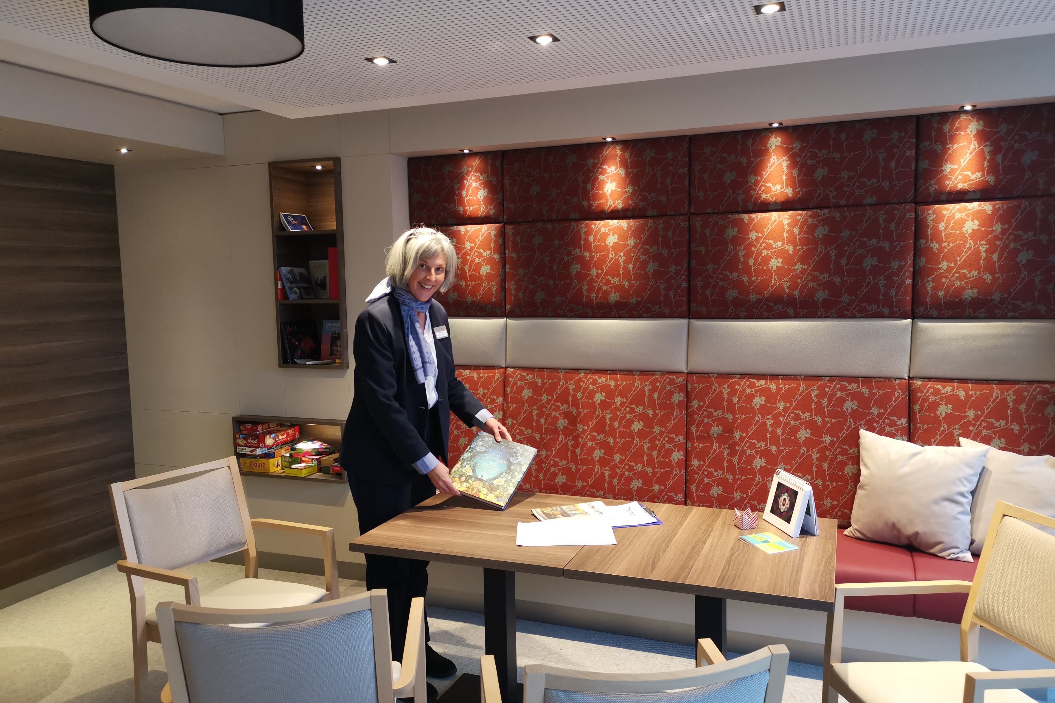 Augustinum Seniorenresidenzen Salon Eine Salon-Gastgeberin steht lächelnd neben einem Tisch