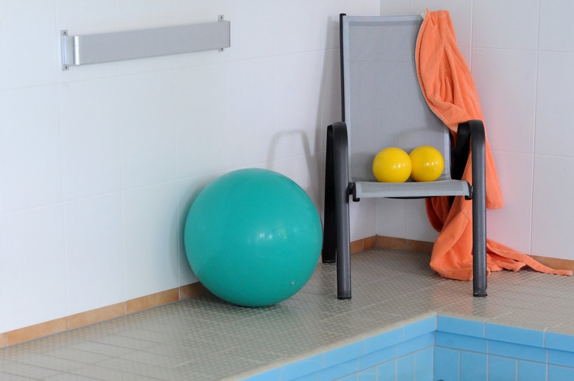 Aquafitness Gymnastikbälle und Stuhl am Rand eines Schwimmbeckens