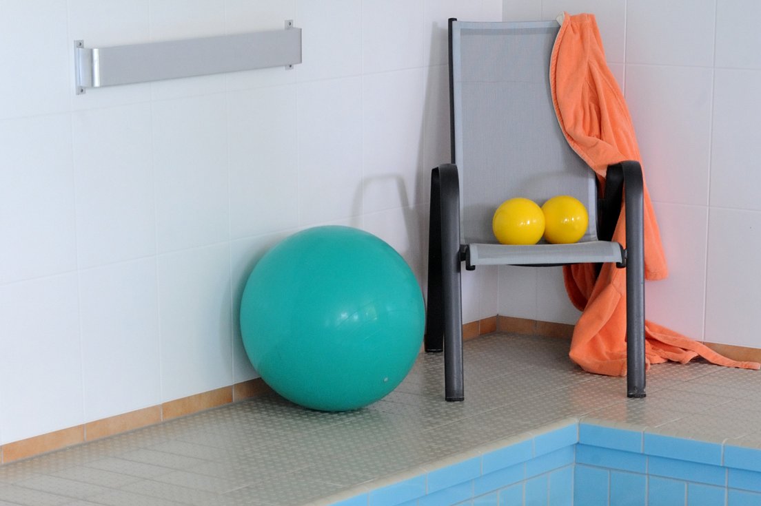 Aquafitness Gymnastikbälle und Stuhl am Rand eines Schwimmbeckens