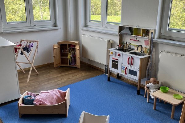 Augustinum Frühförderstelle Puppenspielecke Man sieht eine Puppenspielecke mit Kinderwagen, Einkaufsladen und anderen Gegenständen
