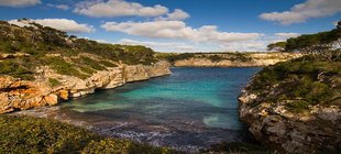 Mallorca & Menorca Eine menschenleere Meeresbucht umgeben von steiniger, grünbewachsener Küste.