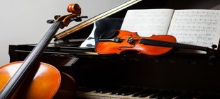 Nachwuchstalente konzertieren Eine Geige liegt auf einem aufgeklappten schwarzen Flügel, ein Cello lehnt daran.