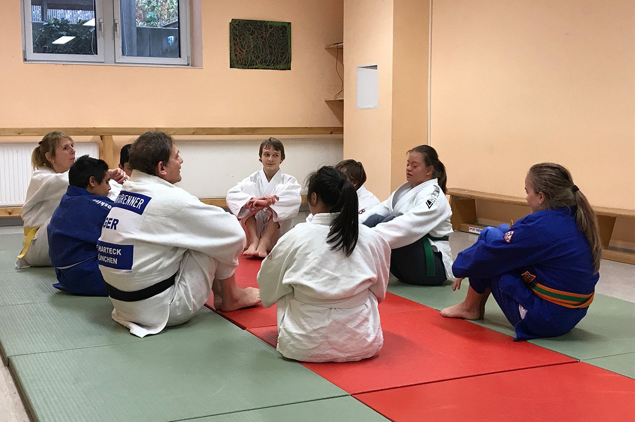 Trainingsbesprechung der ID-Judoka Judoka in typischer Sportkleidung sitzen im Kreis