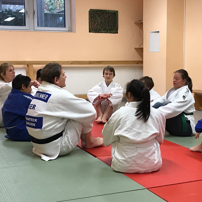 Trainingsbesprechung der ID-Judoka Judoka in typischer Sportkleidung sitzen im Kreis