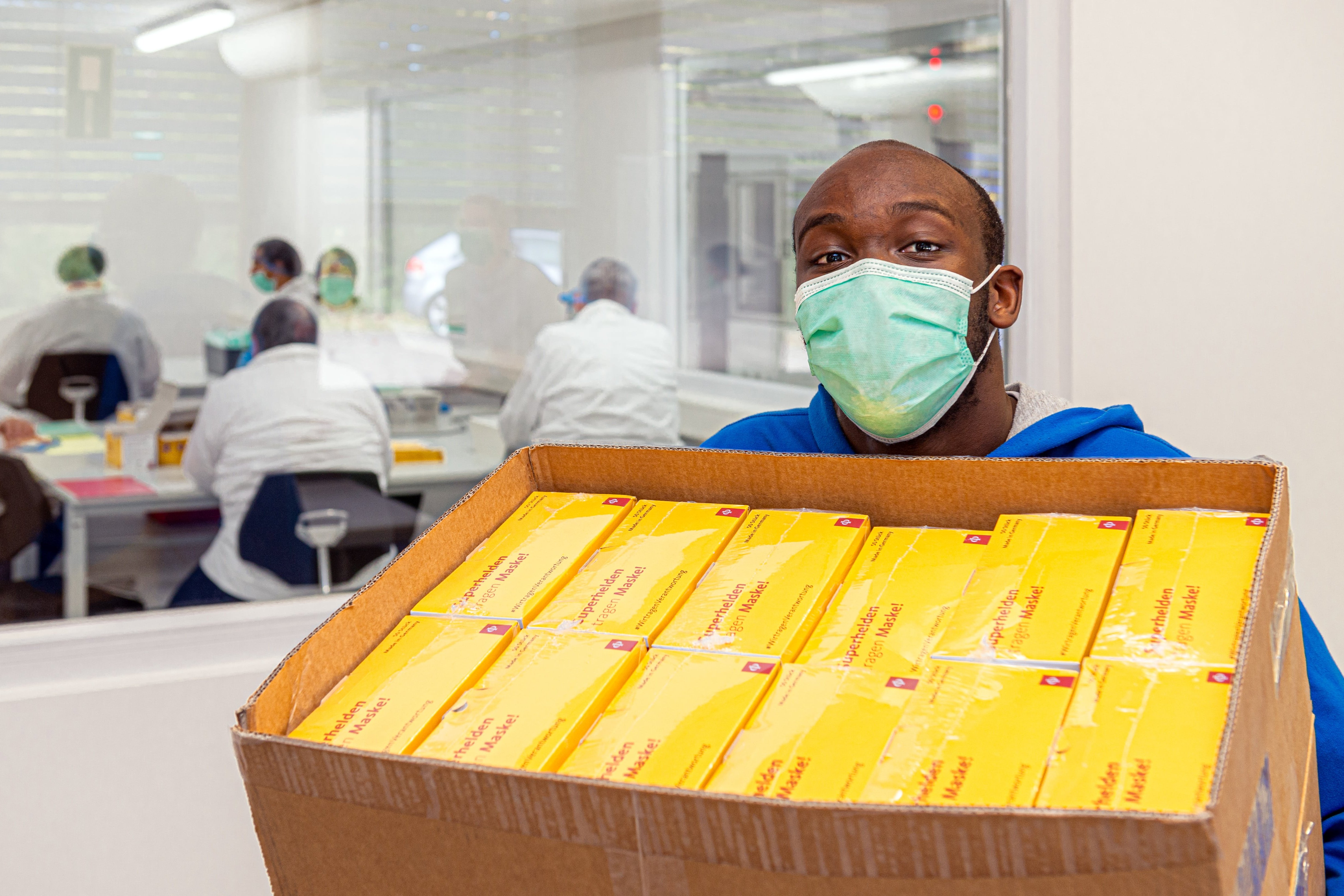 Maskenproduktion Ein Klient hält eine Kiste mit verpackten medizinischen Masken