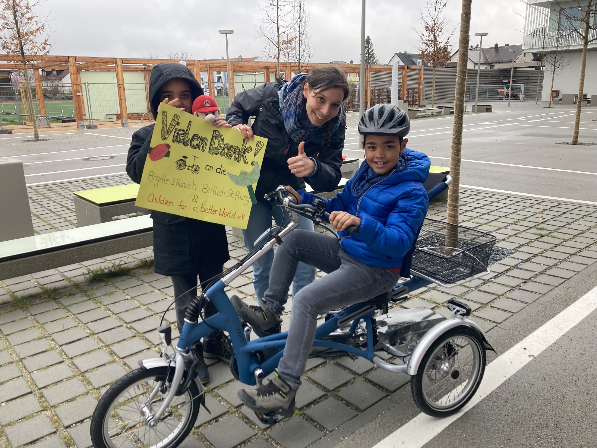 Augustinum Spenden Verkehrsunterricht Zwei Schüler und eine Lehrerin halten beim Verkehrsunterricht ein Plakat in den Händen, auf dem sie sich für die Spenden bedanken